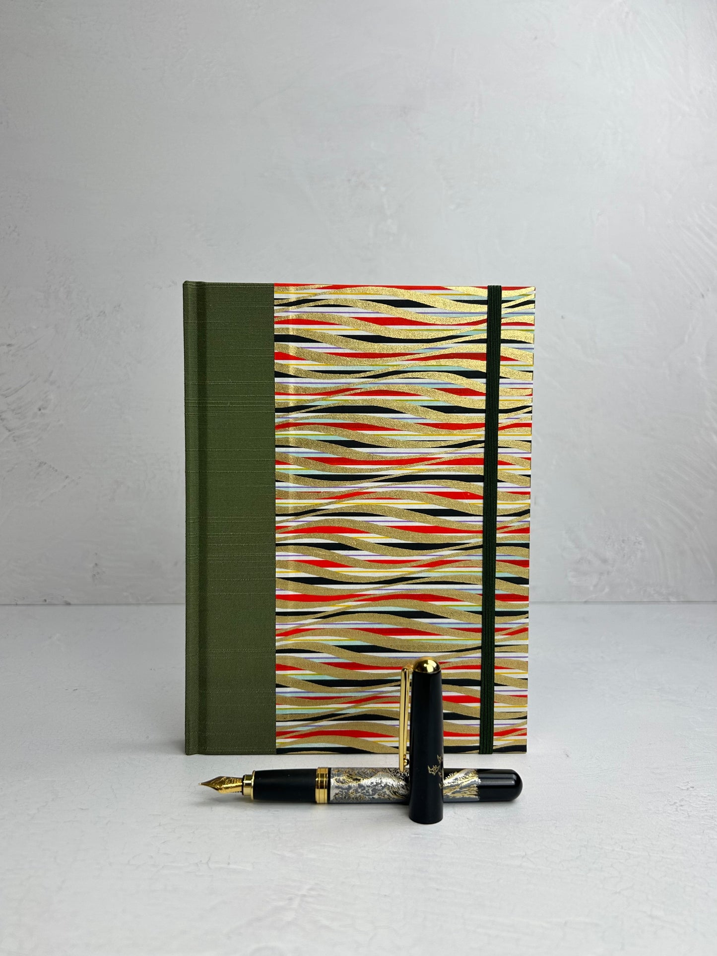 A5 160-page Hardcover Journal finished in olive green Japanese book cloth and gold, black and red geometric Chiyogami Paper