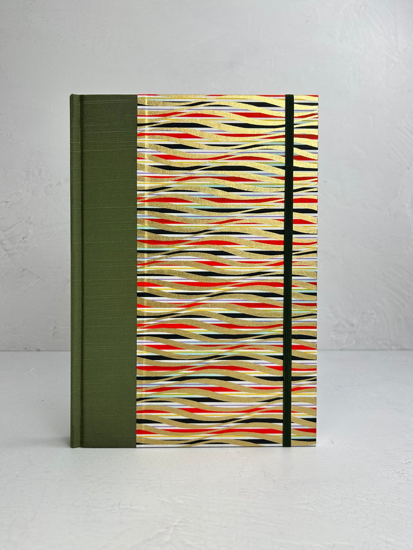 B5 192-page Hardcover Journal finished in olive green Japanese book cloth and gold, black and red geometric Chiyogami Paper